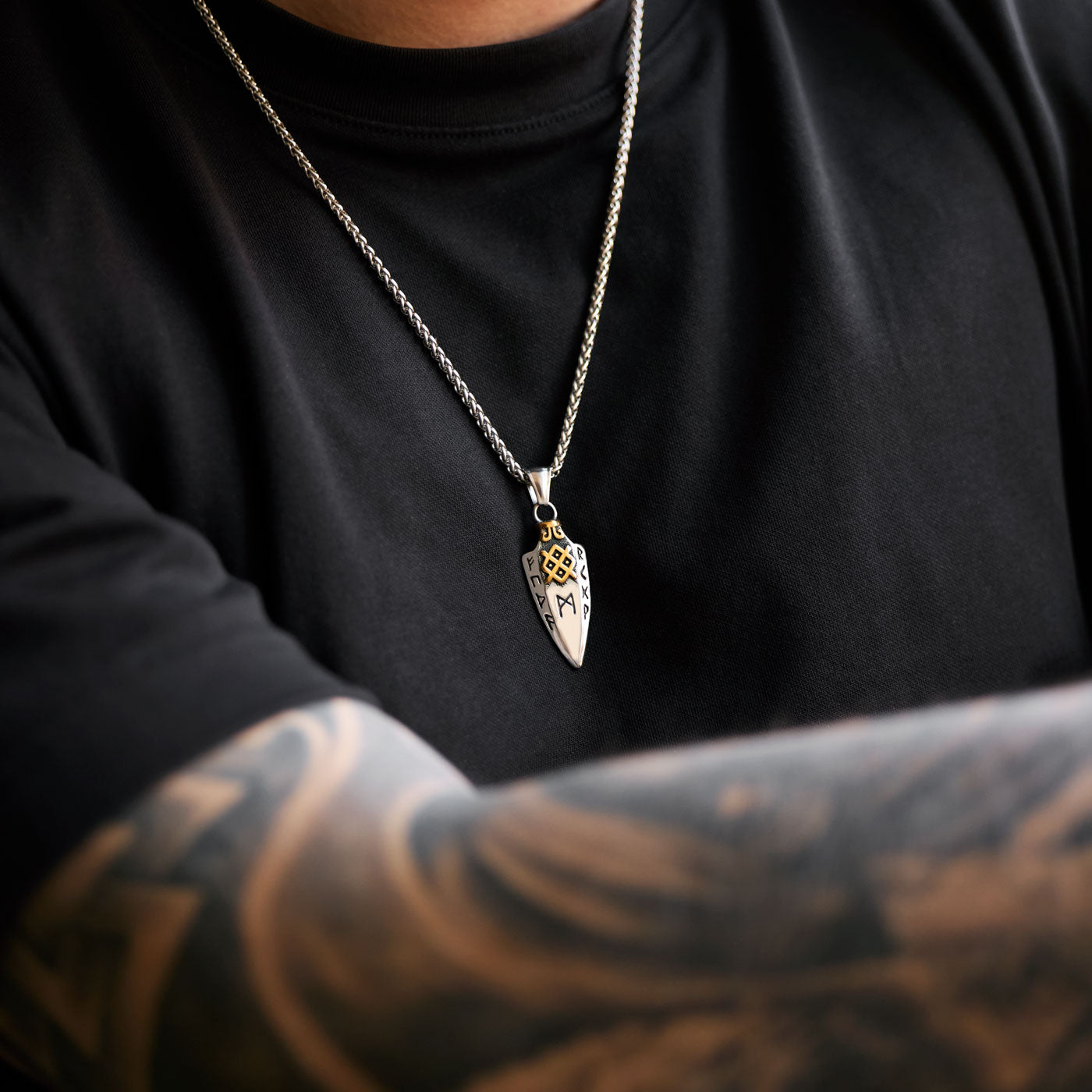 The stainless steel Gungnir spear pendant in gold and silver from Odin Trinkets, worn on a Viking chain necklace, showcasing its bold Norse rune engravings and striking gold accents.