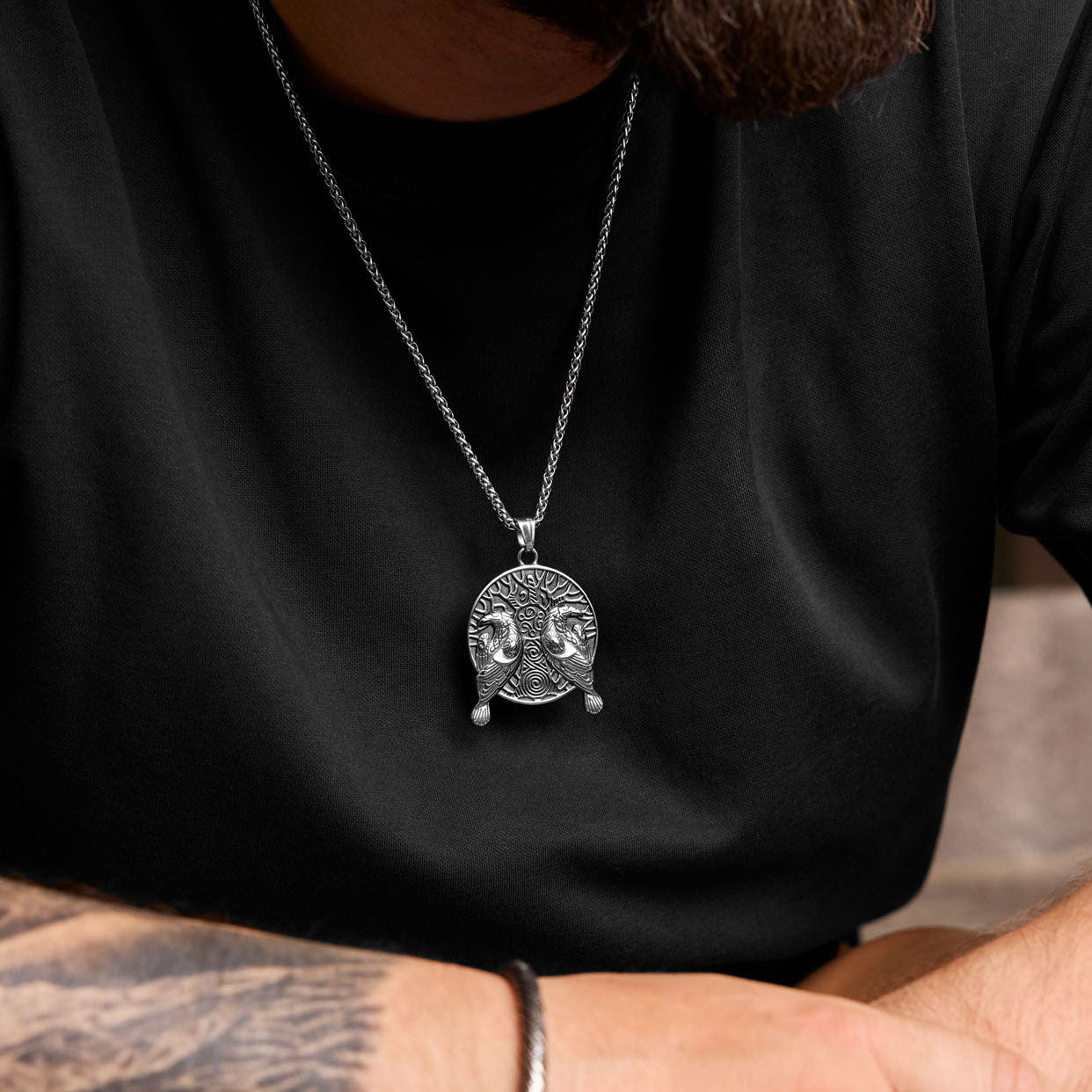 Hugin and Munin necklace worn on chest, showing Viking raven design with Yggdrasil and Norse symbolism.