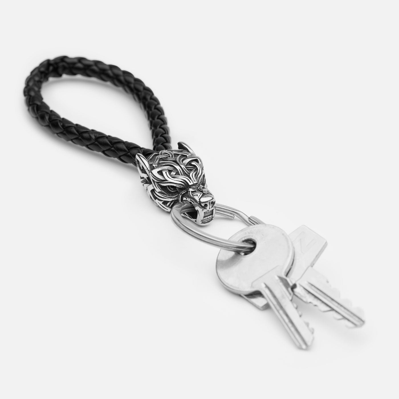 Fenrir knotwork wolf head keychain on braided black leather strap with stainless steel ring holding keys, white background.