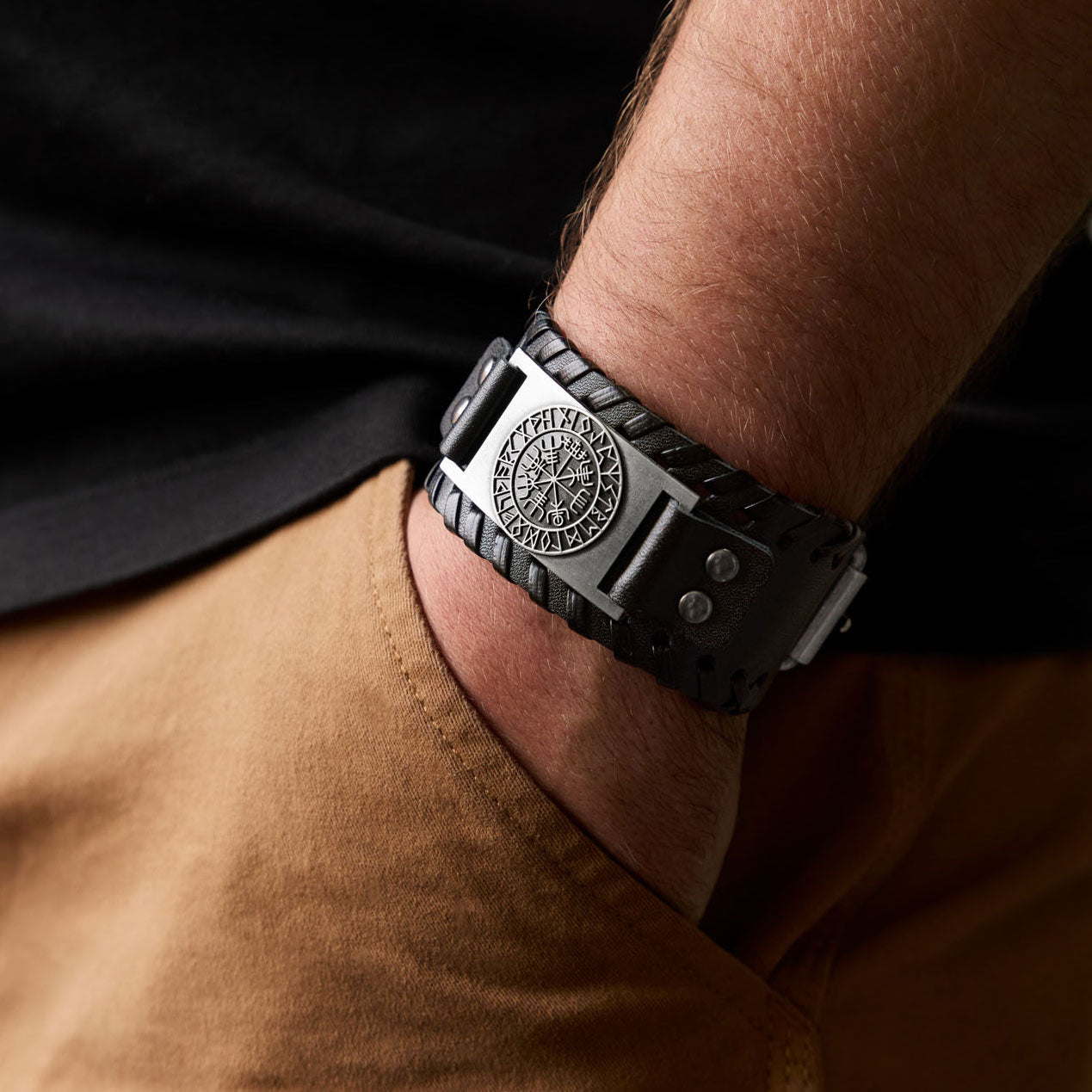 Man wearing Norse leather bracelet with Vegvísir symbol – bold Viking accessory styled with tattooed arm and casual outfit.