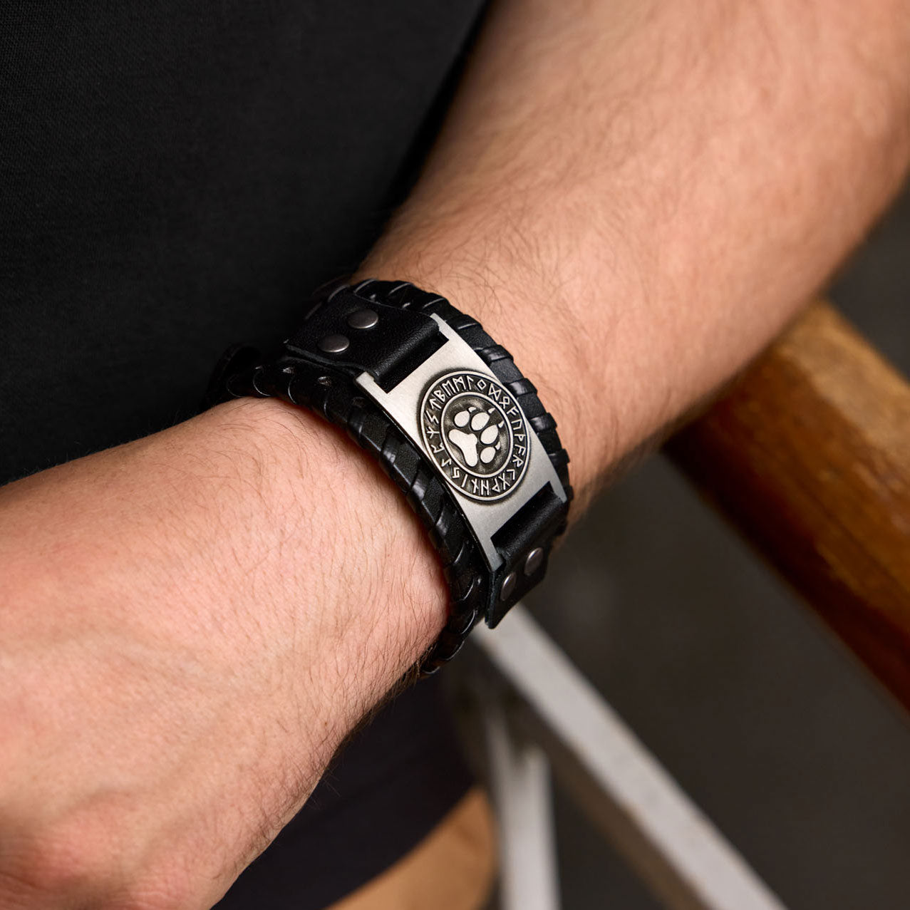 Black Norse leather buckle with bear paw symbol worn on tattooed wrist
