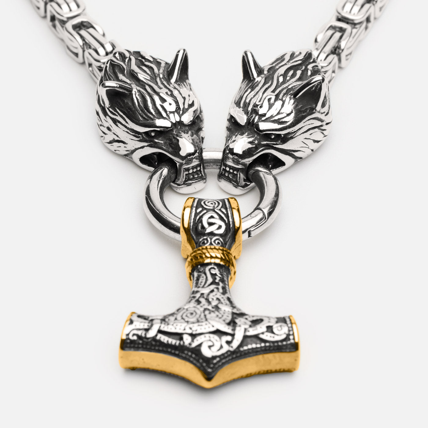 Detailed front view of a Viking necklace featuringa golden Thor's hammer Mjölnir hanging from two wolf heads, attached to a thick kings chain.