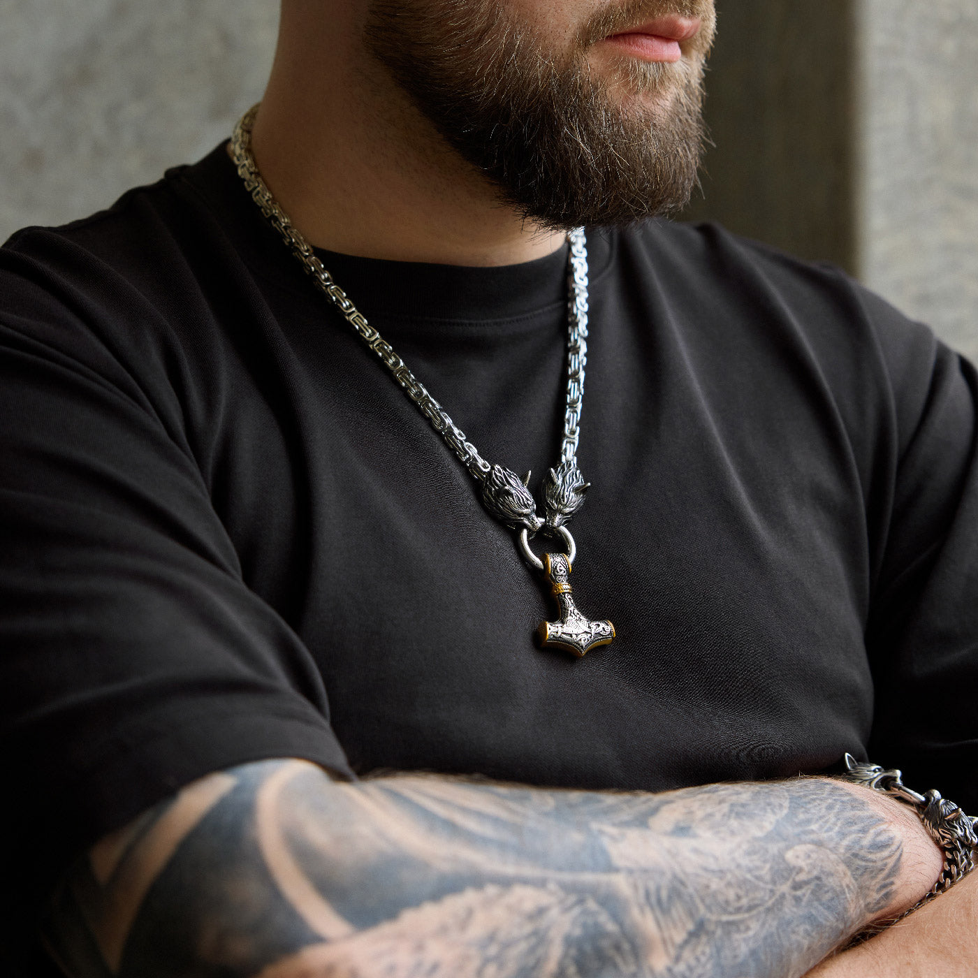 Front view of the stainless steel Mjölnir pendant in gold and silver from Odin Trinkets, featuring intricate Viking engravings, Geri & Freki wolf head clasps, and a bold Norse King’s chain.