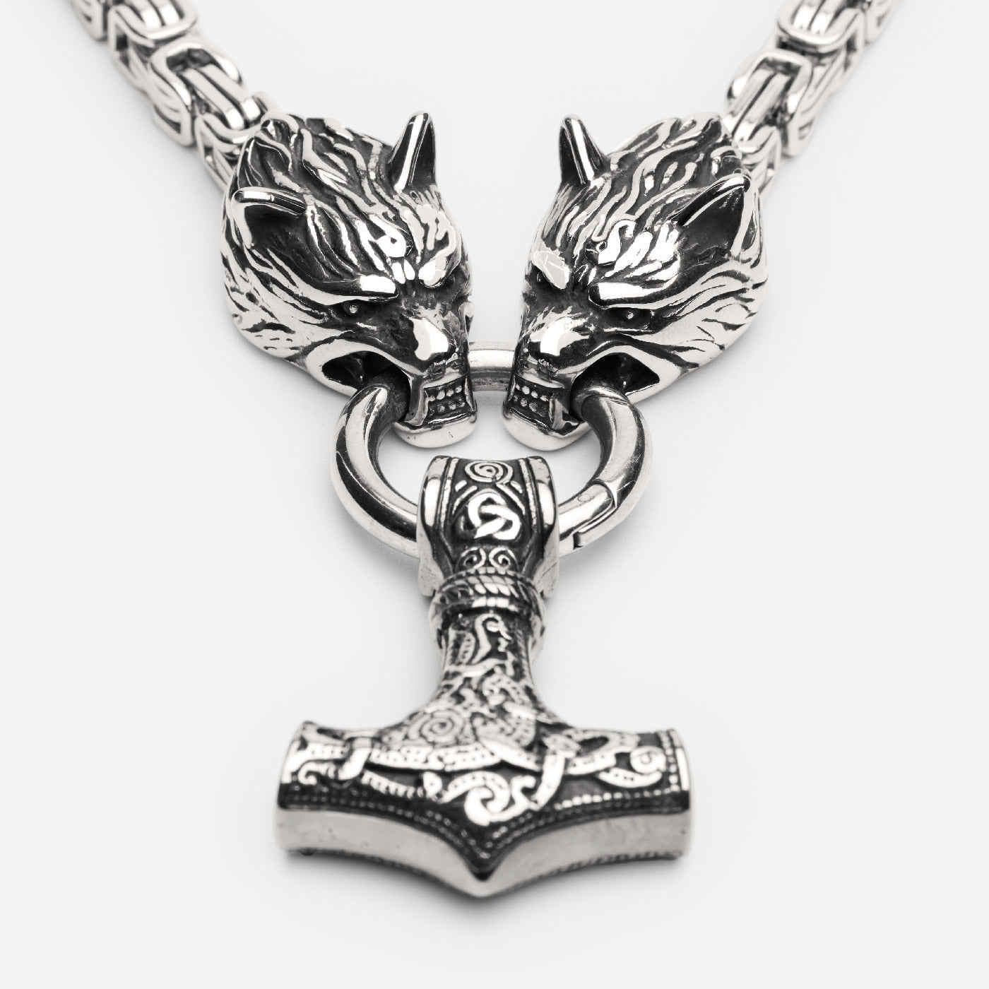 Detailed front view of a Viking necklace featuring Thor's hammer Mjölnir hanging from two wolf heads, attached to a thick keel chain.