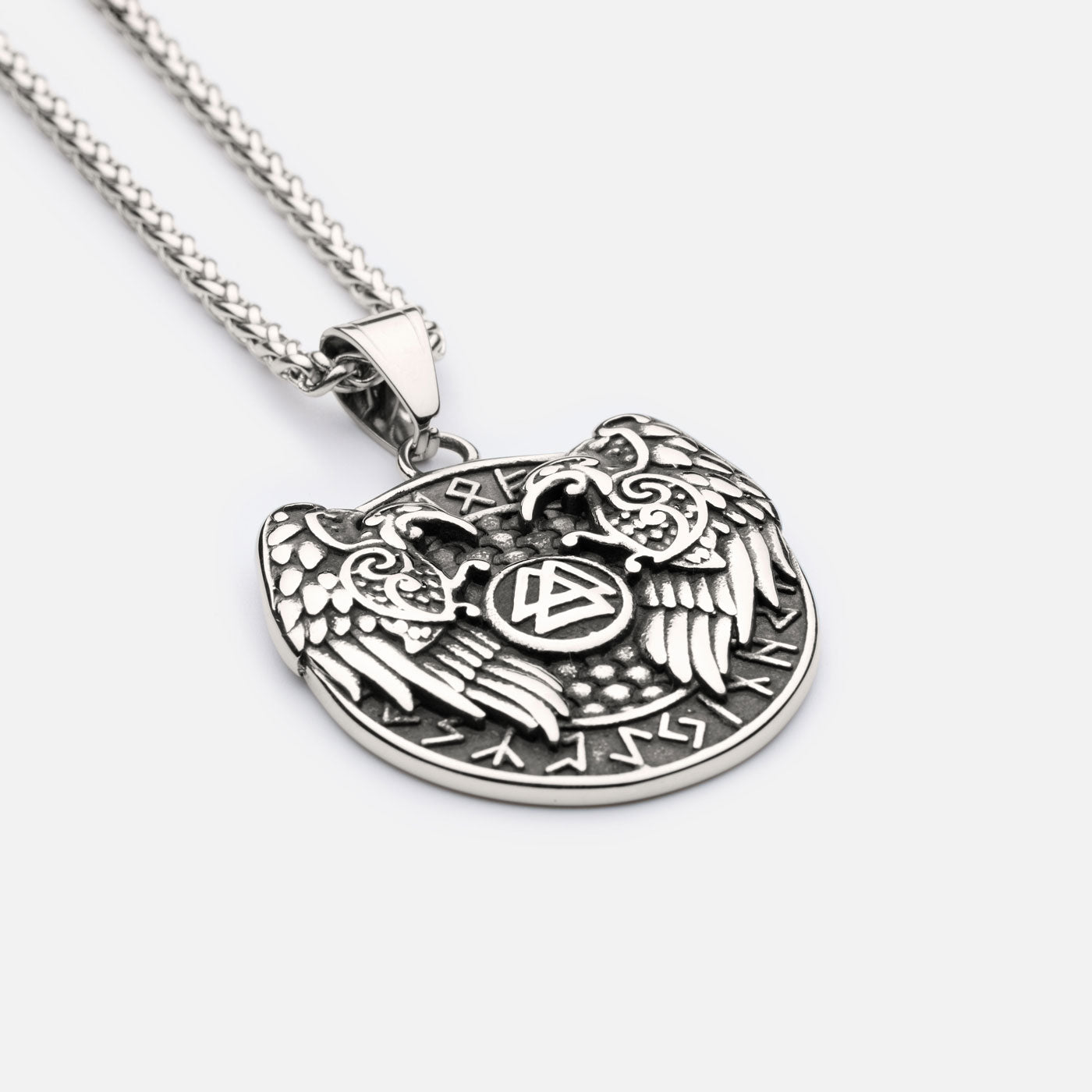 Close-up of Norse raven necklace with detailed carvings of Hugin and Munin guarding the Valknut, crafted in Viking-style relief.