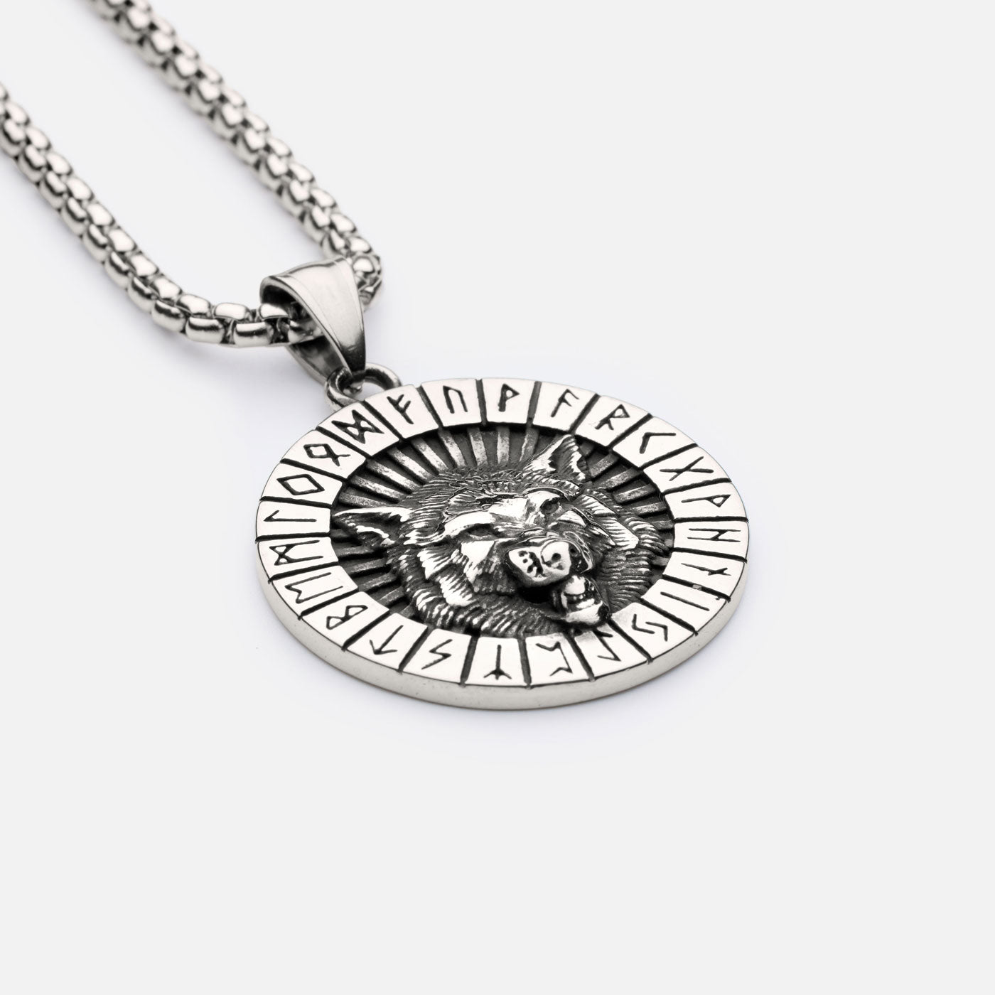 Close-up of Norse wolf necklace with bold box chain, featuring engraved wolf head and circular Elder Futhark rune border.