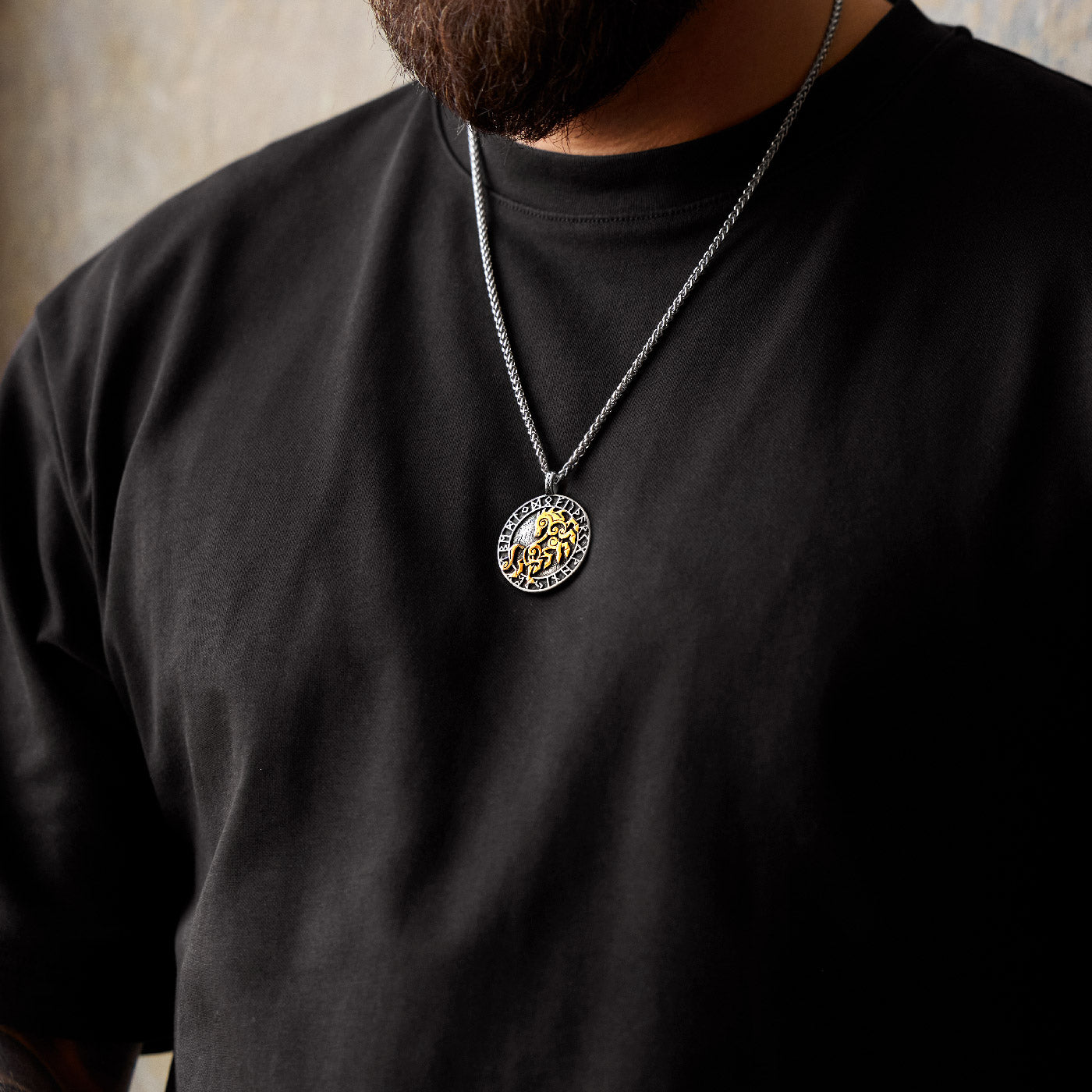 Man wearing a Viking necklace featuring Sleipnir, Odin’s eight-legged horse, surrounded by the Elder Futhark runes, on a silver keel chain.