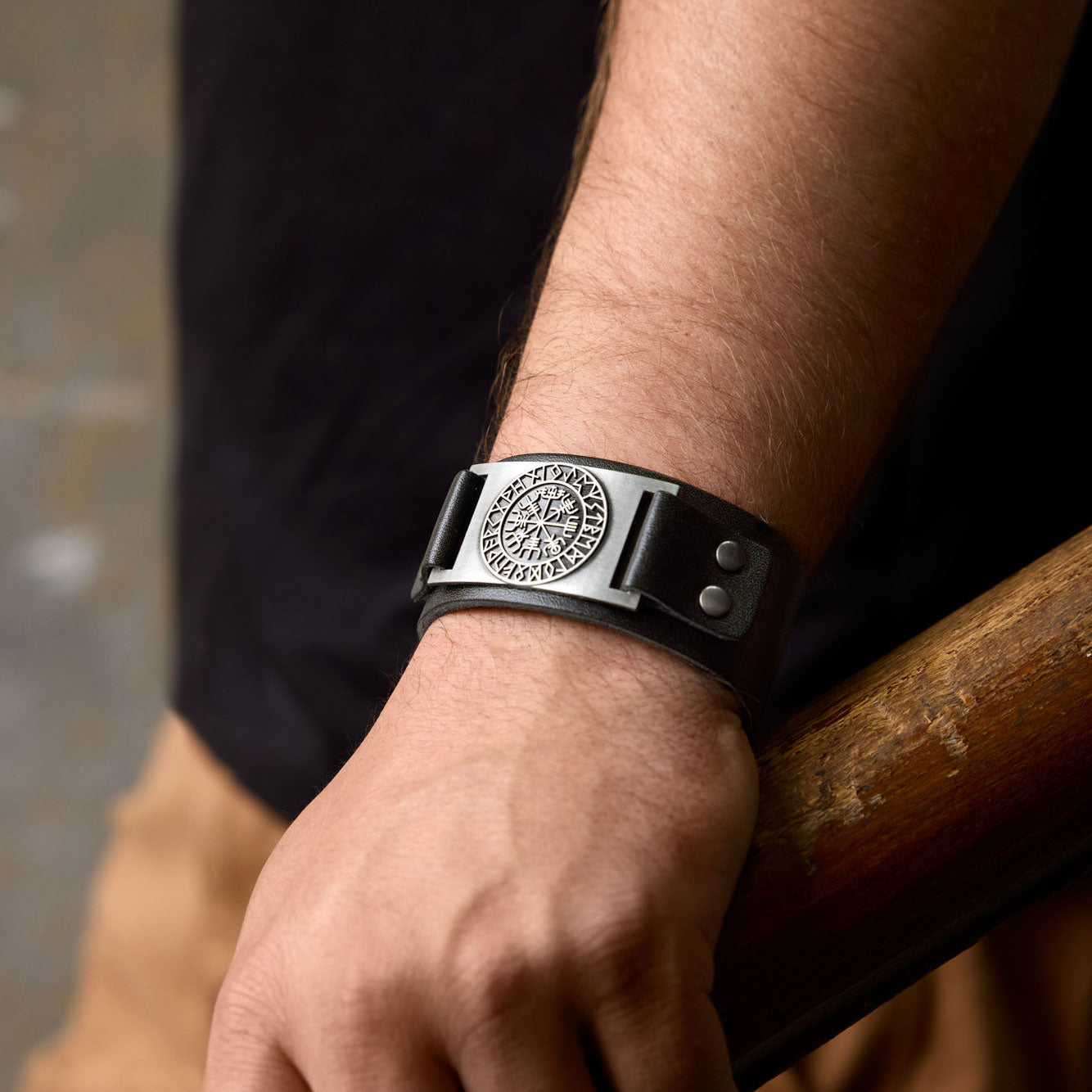 Black leather Viking bracelet with Vegvísir symbol worn on wrist, showing bold Norse accessory in everyday outfit.