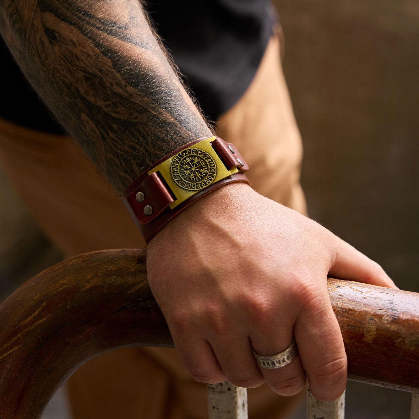 Brown genuine leather Viking bracelet with bronze Vegvísir plate worn on wrist, showing bold Norse style and snap button closure.