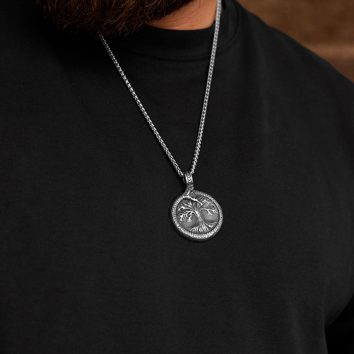 Yggdrasil pendant worn on chain, showing Viking Tree of Life with Jormungandr snake design around it.