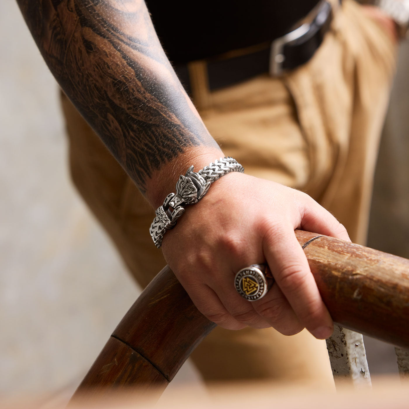 A stainless steel Fenrir wolf bracelet from Odin Trinkets worn on a tattooed wrist, paired with a Valknut ring, embodying the bold spirit of Norse mythology and Viking heritage.