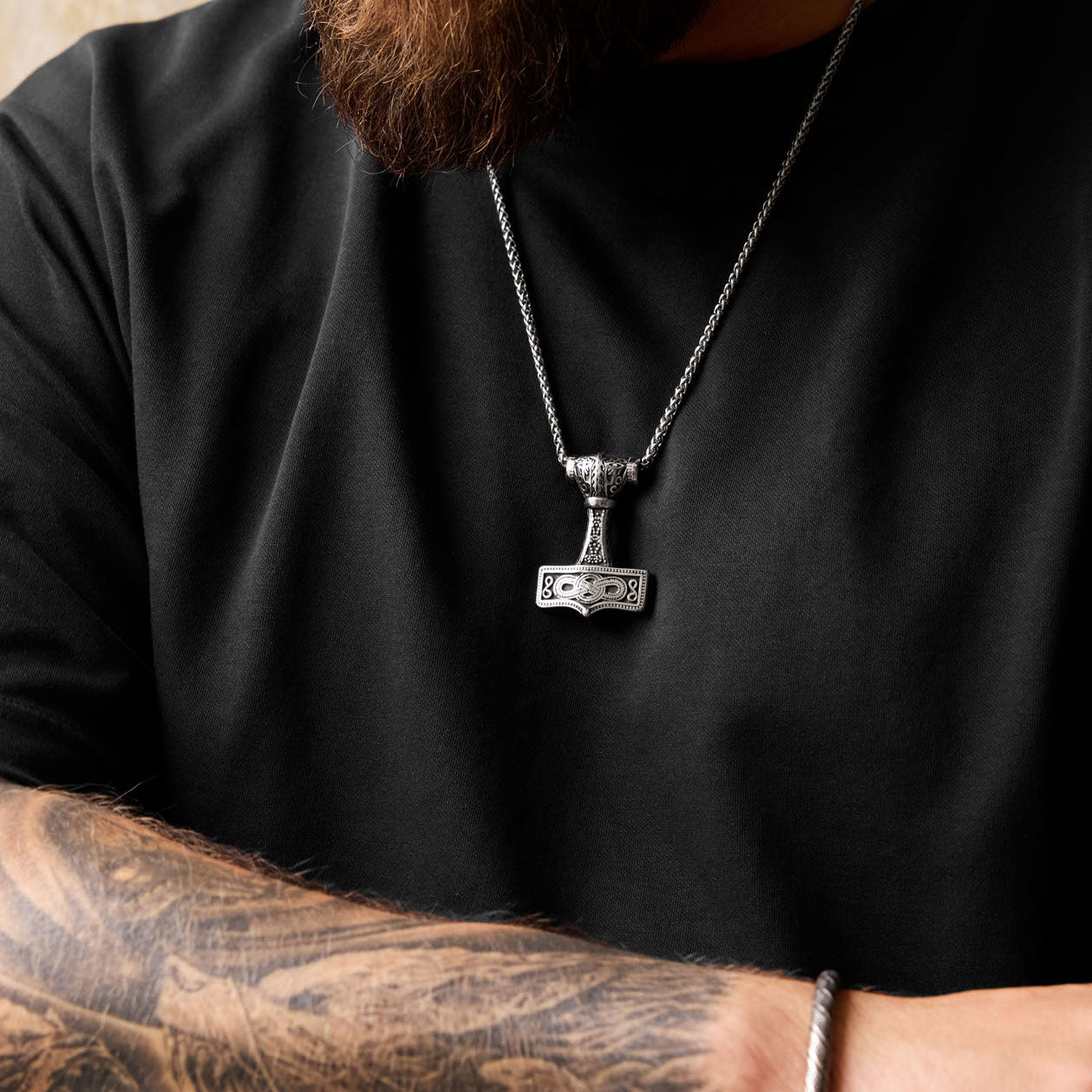 Man wearing the Mjölnir of Asgard necklace with Viking hammer pendant over a black shirt