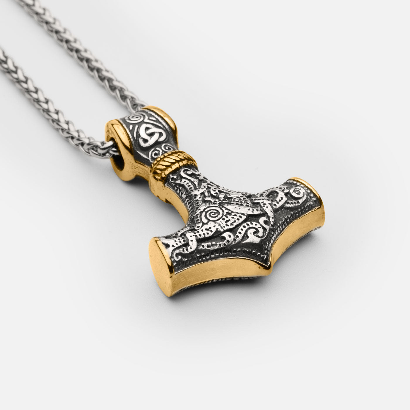 Close-up of the stainless steel Mjölnir pendant in gold and silver from Odin Trinkets, highlighting intricate Norse engravings and a sturdy Viking chain for a bold and timeless look.