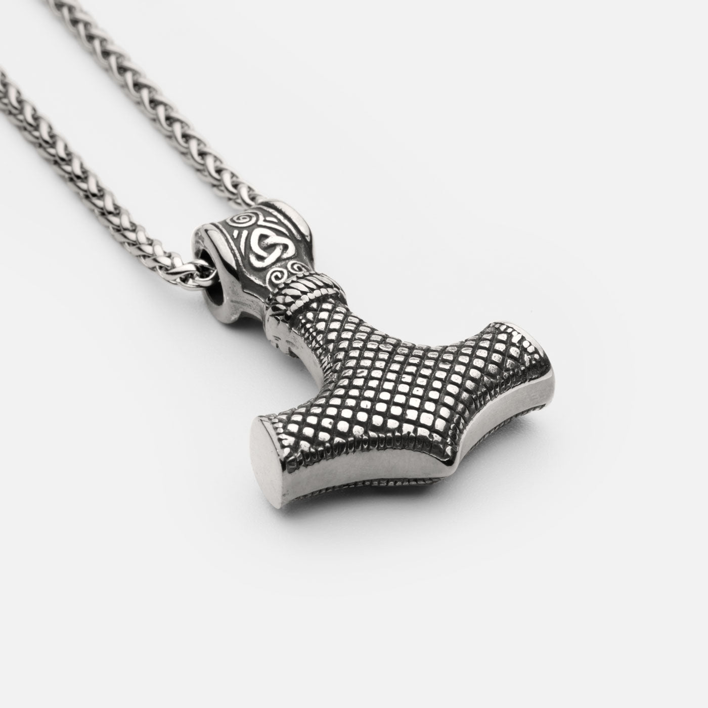 Back view of the stainless steel Mjölnir pendant in silver from Odin Trinkets, showcasing a textured grid pattern and intricate Norse engravings on a simple yet bold Viking chain.