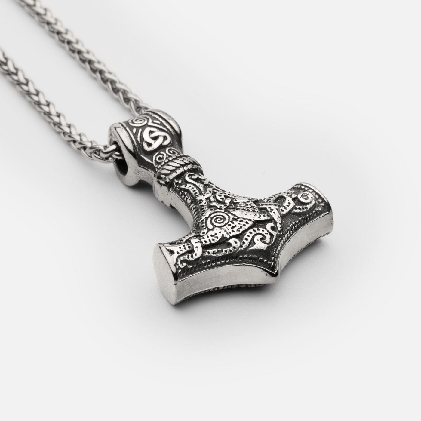 Close-up of the stainless steel Mjölnir pendant in silver from Odin Trinkets, highlighting intricate Norse engravings and a sturdy Viking chain for a bold and timeless look.