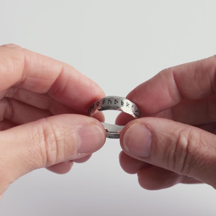 Close-up video of a stainless steel rune ring, featuring deeply engraved Elder Futhark runes on a rugged hammered surface. A bold Viking ring symbolizing wisdom, protection, and ancient Norse power. Crafted for those who honor the runic legacy—an essential piece from Odin Trinkets.