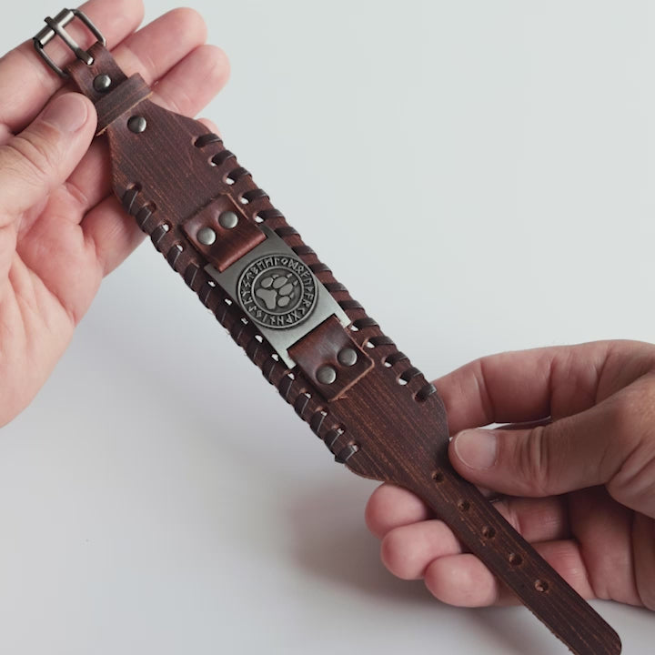 Close-up video of Odin Trinkets close-up video of brown leather Viking bracelet featuring wolf paw symbol surrounded by runes, inspired by Norse mythology, with an adjustable buckle closure for men