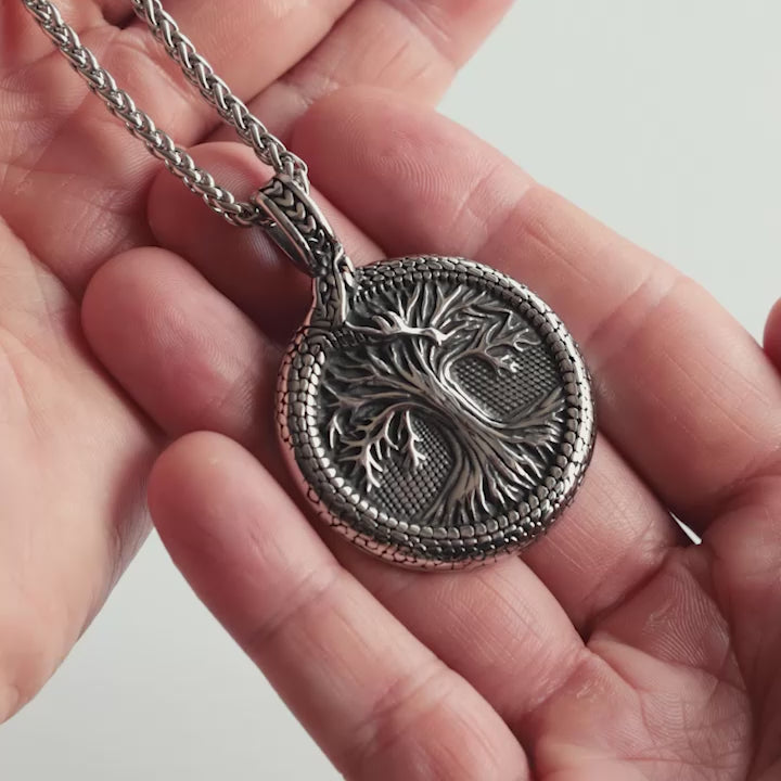 Odin Trinkets close-up video of silver stainless steel Viking necklace featuring Yggdrasil tree of life encircled by Jörmungandr ouroboros, Norse mythology inspired jewelry for men