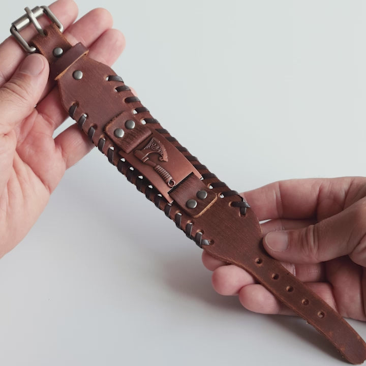 Close-up video of Odin Trinkets brown leather Viking bracelet featuring detailed axe symbol, Norse mythology inspired design, and sturdy belt buckle closure for men