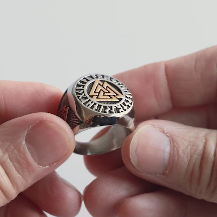 Close-up video of a stainless steel Valknut signet ring, featuring gold-accented details and Elder Futhark runes. This bold Viking seal ring represents Odin’s power, fallen warriors, and Norse heritage. A statement piece for those who carry the spirit of the North crafted with precision by Odin Trinkets.