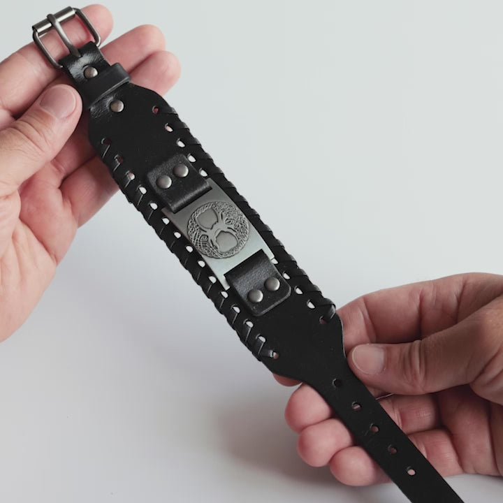 Close-up video of Odin Trinkets close-up video of black leather Viking bracelet featuring the Yggdrasil tree of life from Norse mythology, highlighted with an adjustable buckle closure for a bold look