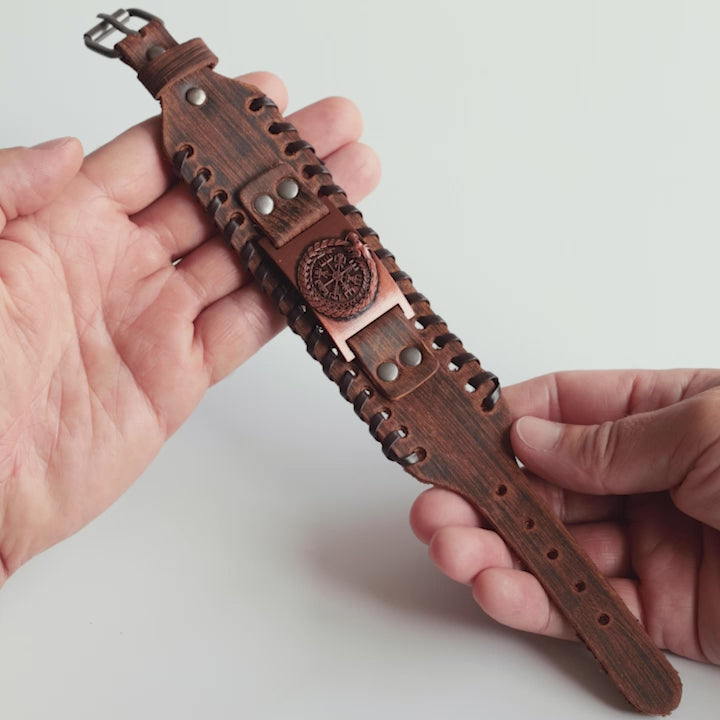 Close-up video of Odin Trinkets close-up video of brown leather Viking bracelet featuring the Norse serpent Jörmungandr encircling the Vegvisir compass, with an adjustable buckle closure for a bold Viking look