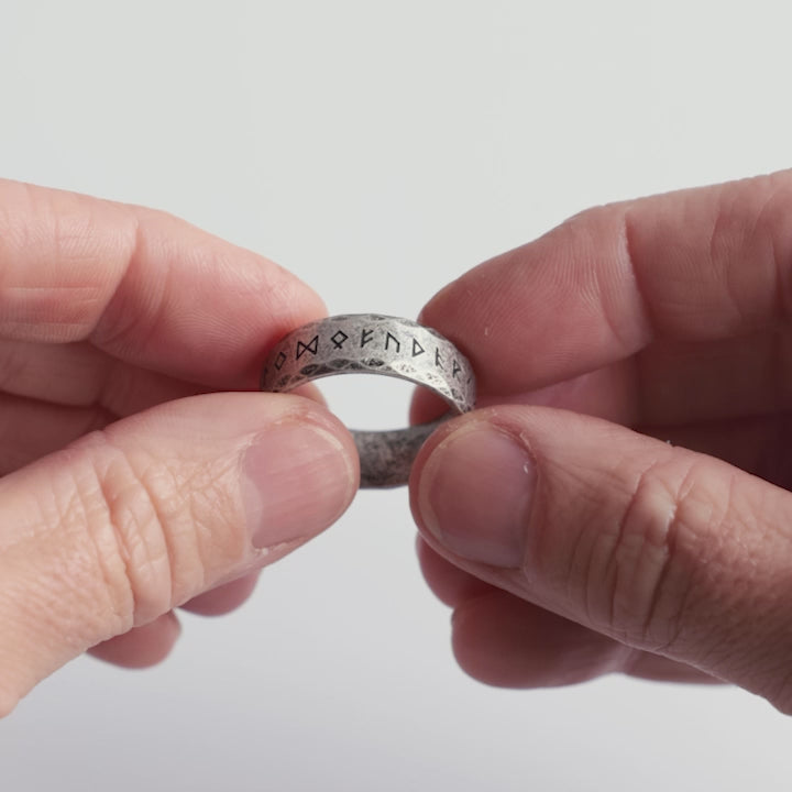 Close-up video of a stainless steel rune ring with an aged, weathered finish, engraved with Elder Futhark runes. A rugged Viking ring representing wisdom, power, and Norse heritage. Designed for those who embrace the strength of the ancients—crafted with authenticity by Odin Trinkets.