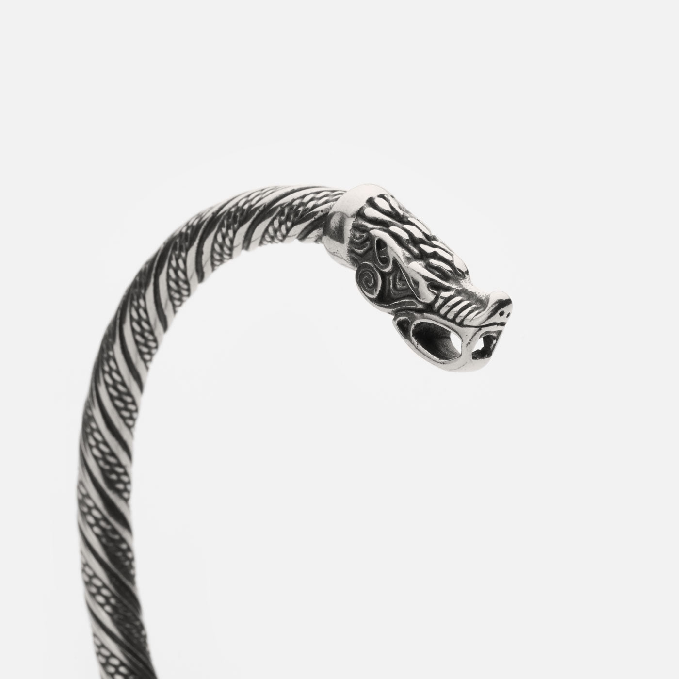 Close-up of a wolf's head on the end of a Viking-style twisted bracelet. The bracelet features intricate detailing along the band, with the wolf's face showcasing detailed craftsmanship.