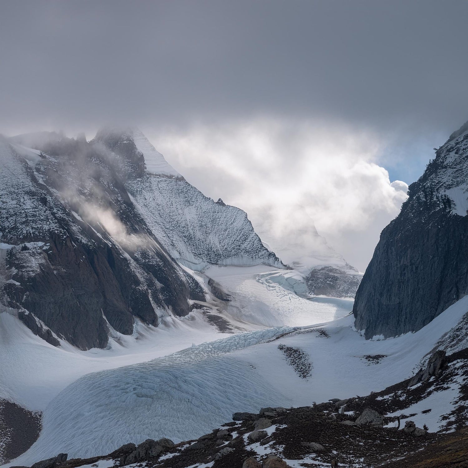 An icy mountain landscape inspired by the mythical realm of Jotunheim, featuring snow-covered peaks and a dramatic glacier under a cloudy sky, evoking the harsh and majestic environment of Norse mythology.