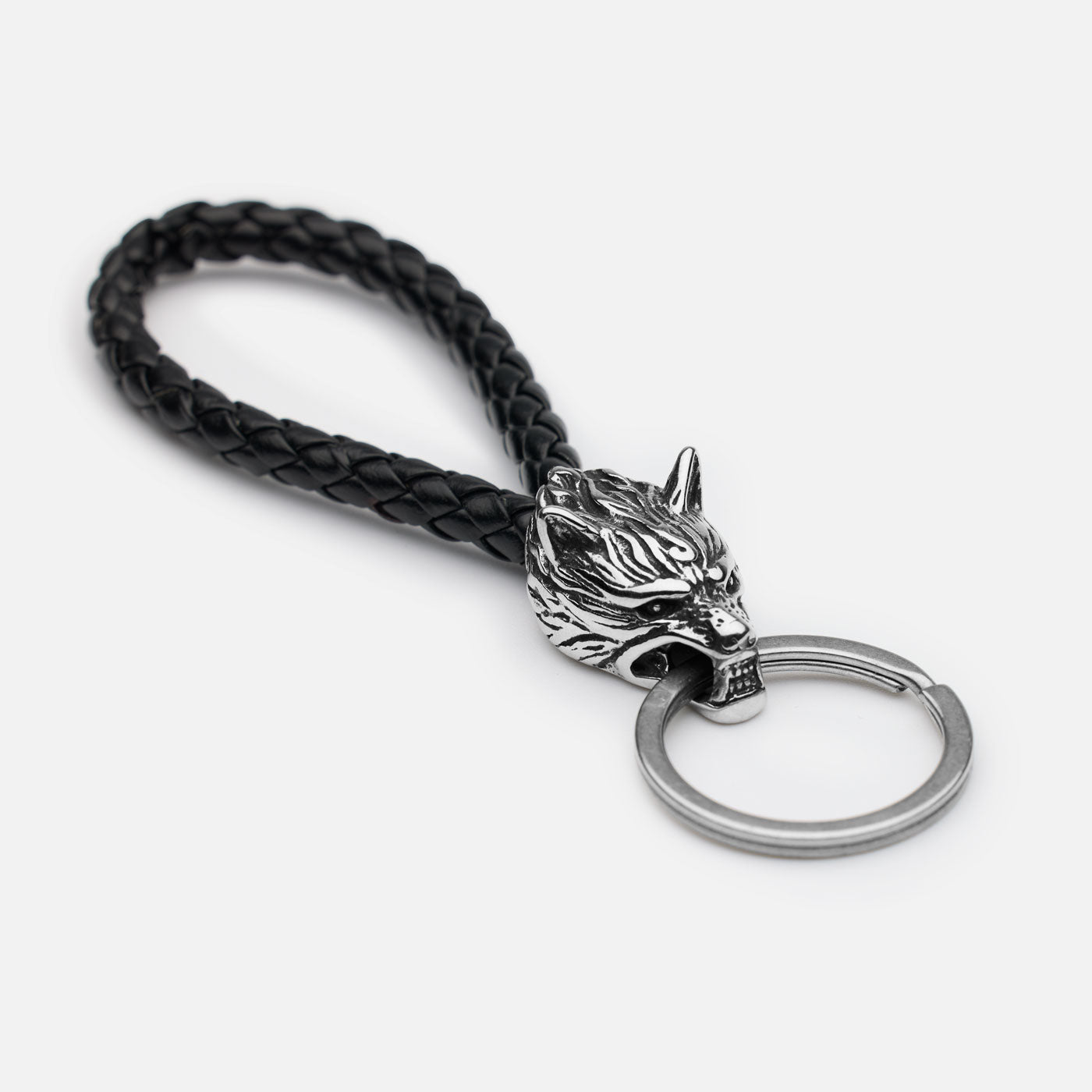 Norse-style wolf head keychain with braided black leather loop and stainless steel split ring, close-up on white background.