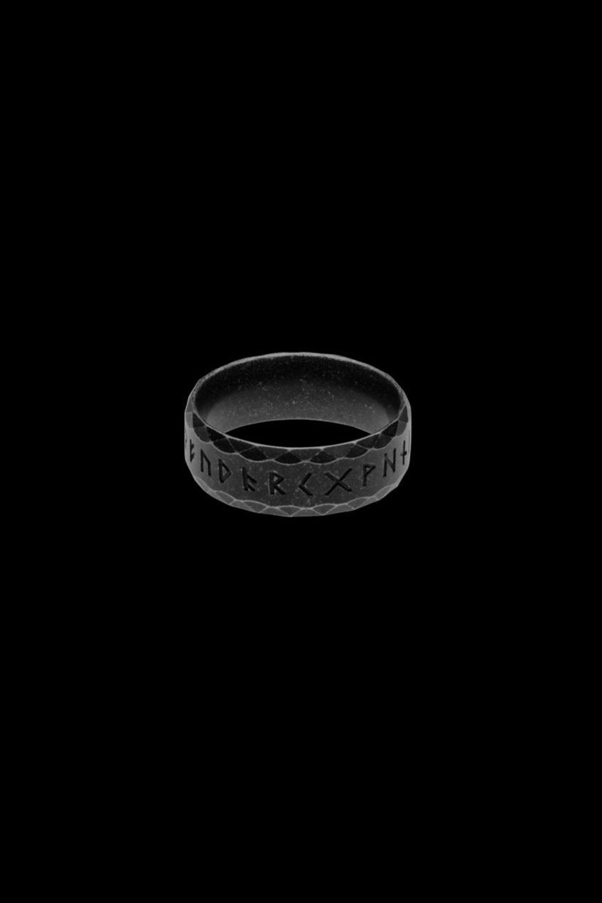 A black stainless steel rune ring, known as the "Antique" variation, featuring the engraved Elder Futhark alphabet. Its dark matte finish and faceted texture provide a bold yet mystical representation of Norse heritage.