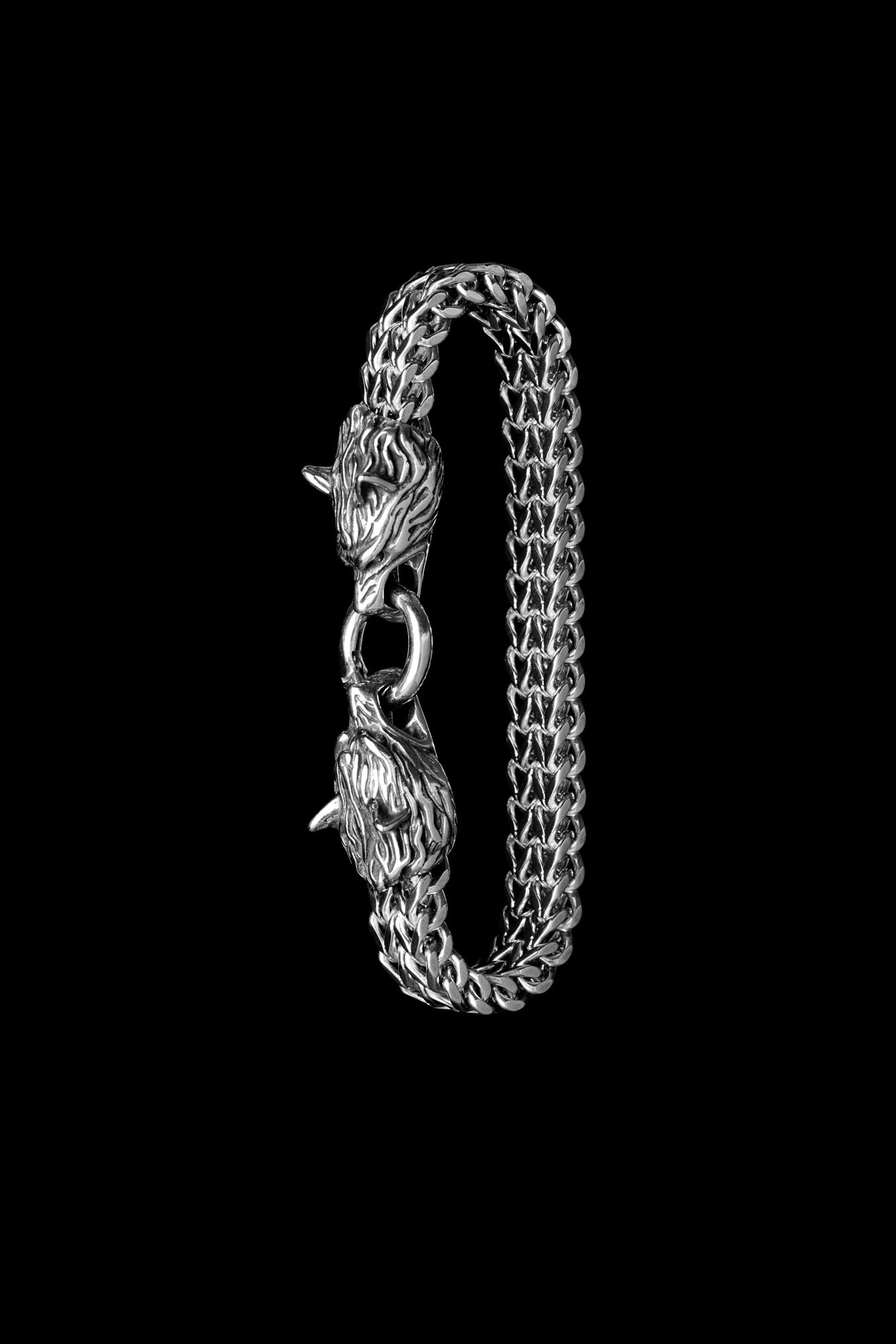 Geri and Freki bracelet featuring two wolf head clasps connected by a metal ring, inspired by Norse mythology, displayed vertically on a black background. Available at Odin Trinkets.