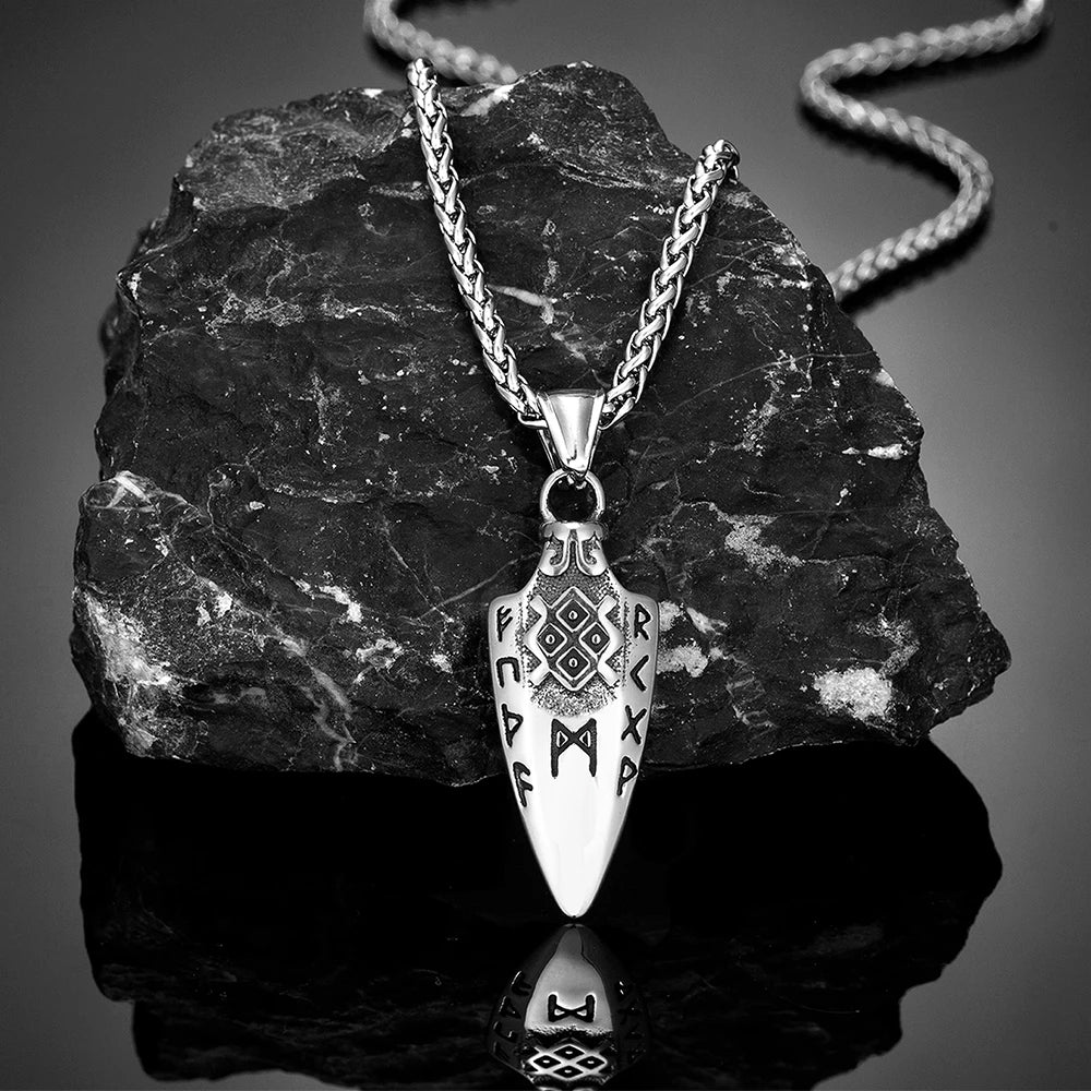 Gungnir necklace with a spearhead pendant engraved with Nordic runes, displayed elegantly against a black stone backdrop with reflective surface. Inspired by Odin's legendary spear. Available at Odin Trinkets.