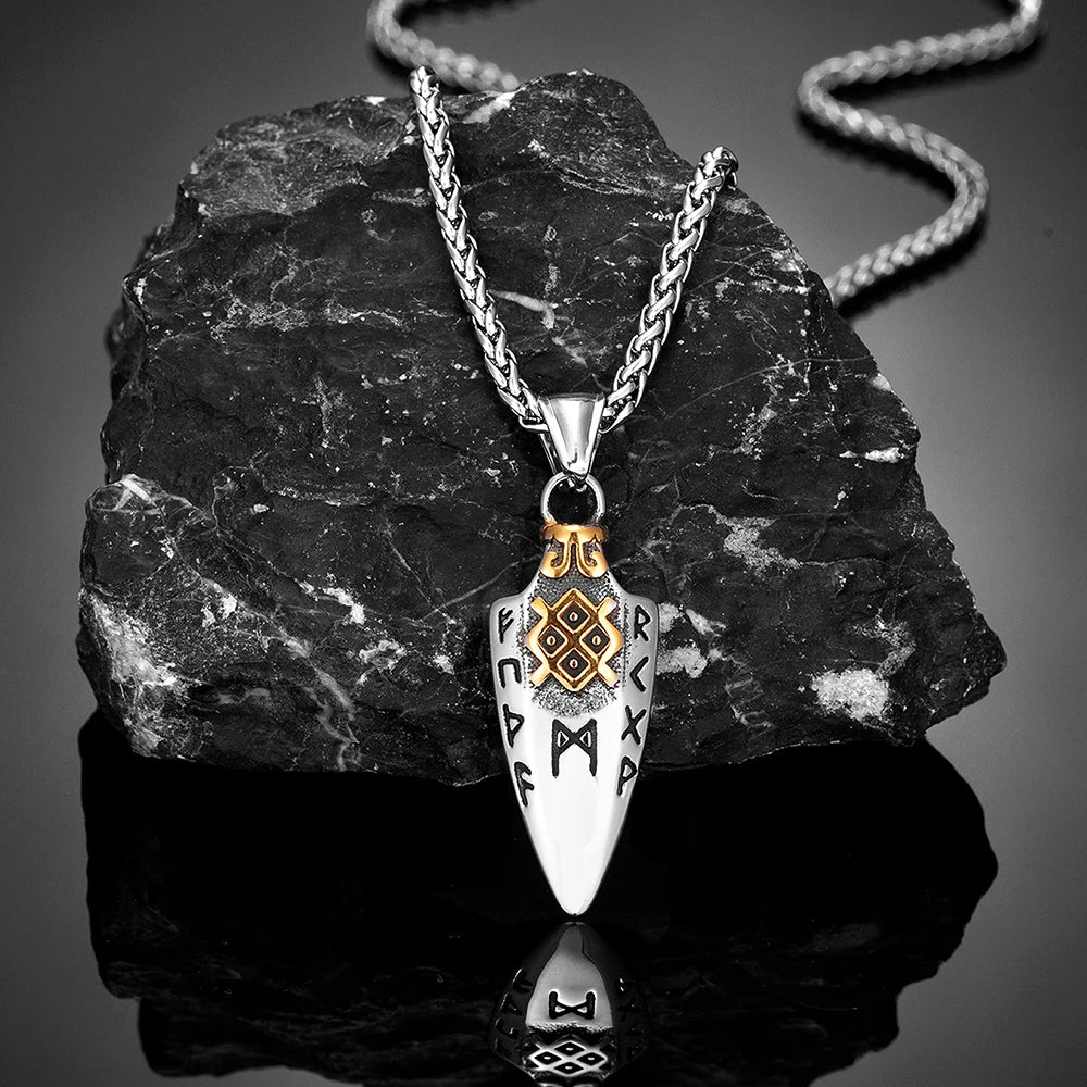 Gungnir necklace with a spearhead pendant engraved with Nordic runes, featuring gold accents, displayed against a black stone backdrop with a reflective surface. Inspired by Odin's legendary spear. Available at Odin Trinkets.