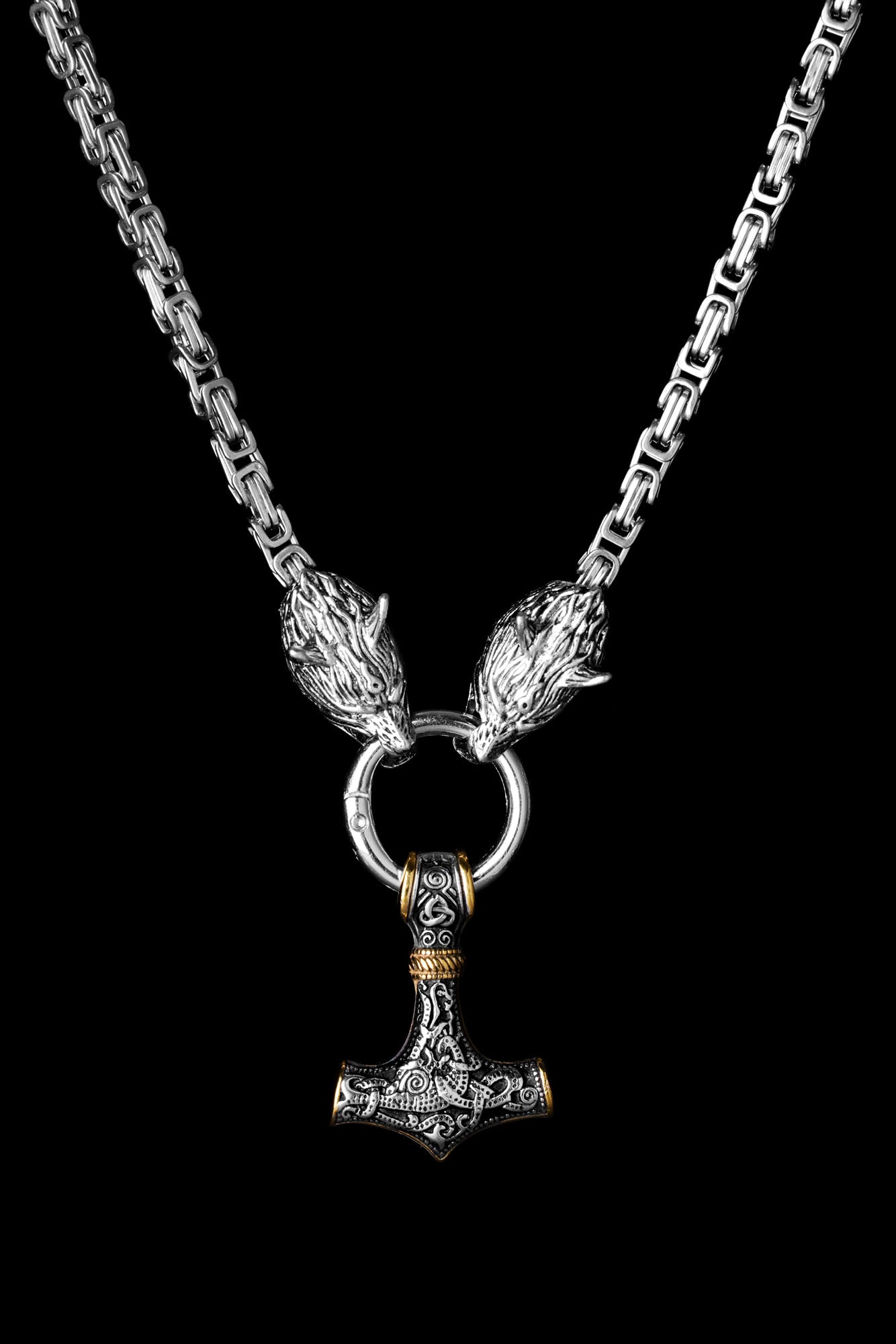 Mjölnir necklace with a Thor's Hammer pendant featuring intricate engravings and gold accents paired with a king chain and wolf head clasps representing Geri and Freki the legendary wolves from Norse mythology displayed on a transparent background Available at Odin Trinkets