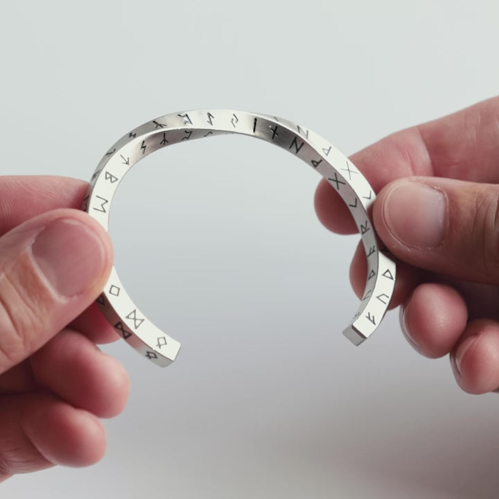 Close-up video of a silver stainless steel rune bracelet, engraved with the Elder Futhark runes. A minimalist yet powerful Viking cuff symbolizing wisdom, protection, and connection to Norse heritage. A timeless piece crafted for those who embrace ancient symbols—designed by Odin Trinkets.
