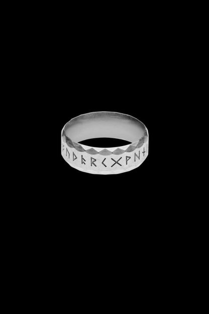 A silver-colored stainless steel rune ring, referred to as the "Silver" variation, featuring the complete Elder Futhark alphabet engraved around the band. The faceted texture adds depth and a blend of modern and ancient design elements.