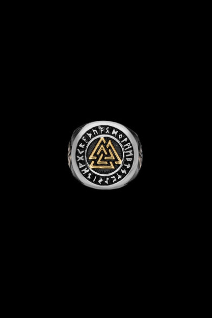 A stainless steel ring with a central Valknut symbol highlighted in gold, encircled by engraved Elder Futhark runes. The design embodies Norse heritage and mythology, available at Odin Trinkets.