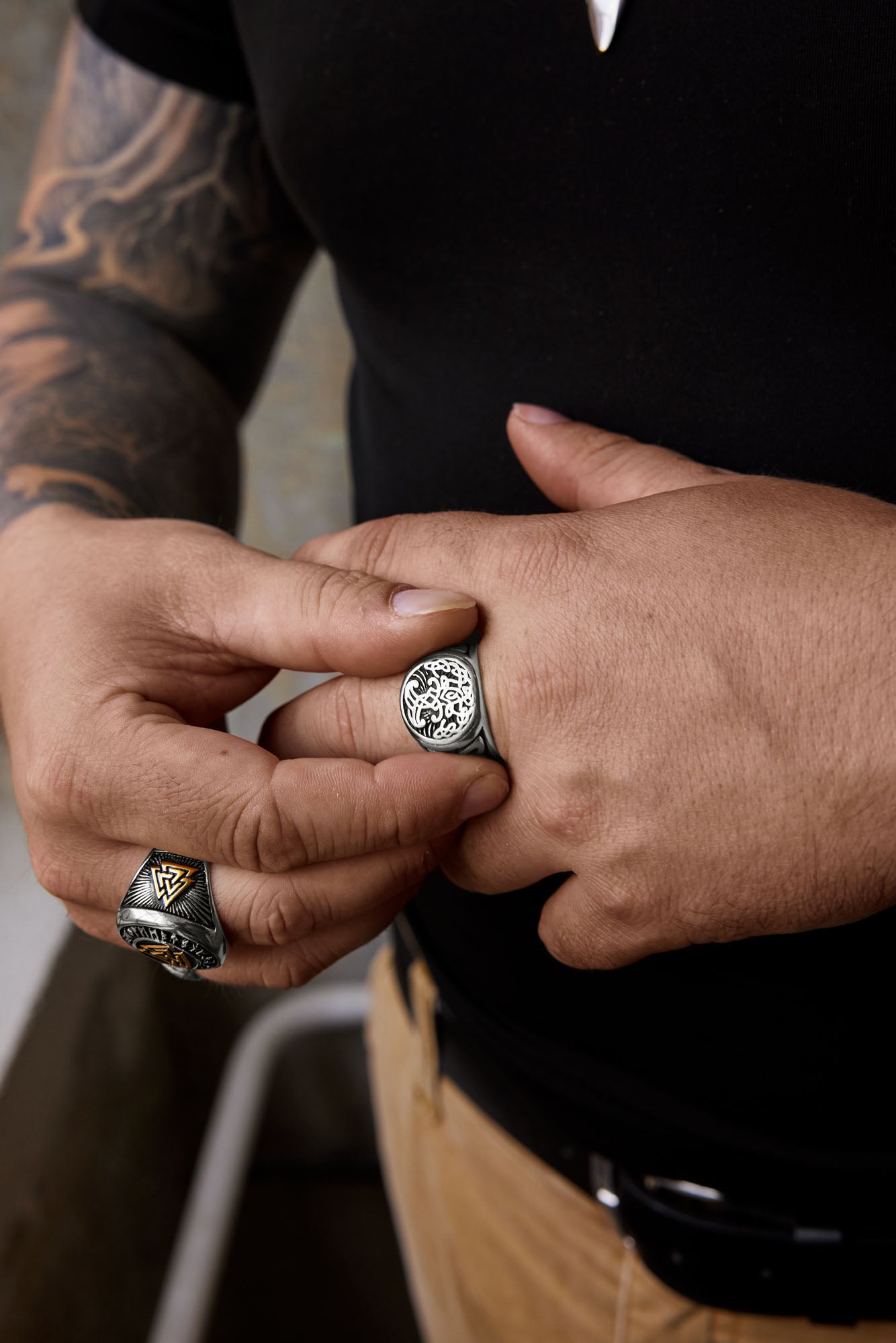 Hands displaying two stainless steel rings from Odin Trinkets: the Yggdrasil Tree of Life ring, featuring a detailed tree design symbolizing interconnectedness, and the Valknut ring with gold and black accents, representing Odin and Norse mythology.